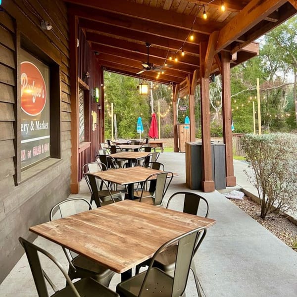 Pudgee's Eatery and Market outdoor patio with wooden tables, metal chairs, and string lights.